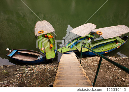 boats and canoes are moored near the river bank 123359443