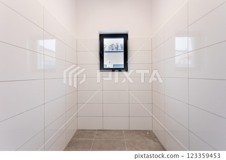 A minimalist room with a large window and tiled walls, creating a clean, calm aesthetic 123359453