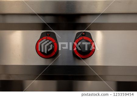 A detailed closeup view of the control knobs on modern kitchen equipment in a contemporary kitchen A detailed closeup view of the control knobs on modern kitchen equipment in a contemporary kitchen 123359454