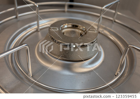 A detailed closeup view of a modern stainless steel gas burner featuring a protective grate 123359455