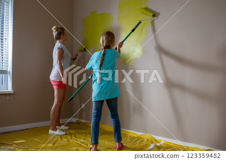 Two Individuals Engaged in Painting a Room with a Bright and Cheerful Yellow Color 123359482