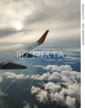 beautiful thick clouds in the sky from the height of the flight of the plane with a view of the wing with engines 123359502