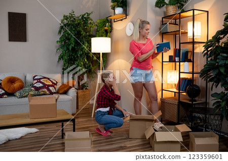 Friends Collaborating to Organize a Cozy and Comfortable Living Space Using Colorful Boxes Friends Collaborating to Organize a Cozy and Comfortable Living Space Using Colorful Boxes 123359601