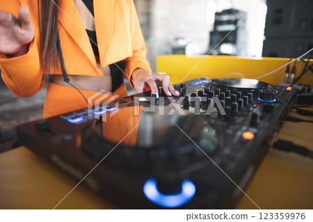 a DJ plays music on a controller at a party a DJ plays music on a controller at a party 123359976