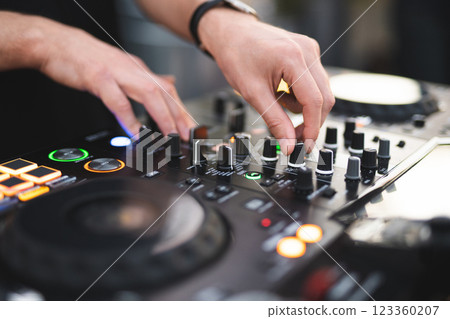 a DJ plays music on a controller at a party a DJ plays music on a controller at a party 123360207