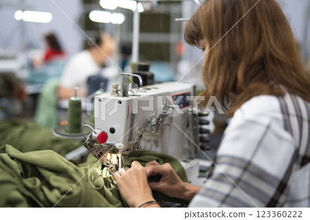workers in an industrial garment factory sew clothes on sewing machine workers in an industrial garment factory sew clothes on sewing machine 123360222