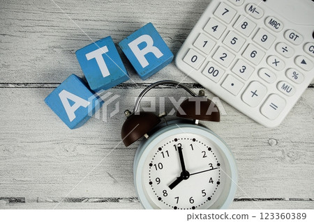 ATR (Average True Range) text with alarm clock and calculator on wooden background 123360389