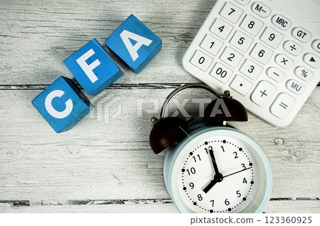 CFA (Chartered Financial Analyst) text with alarm clock and calculator on wooden background CFA (Chartered Financial Analyst) text with alarm clock and calculator on wooden background 123360925
