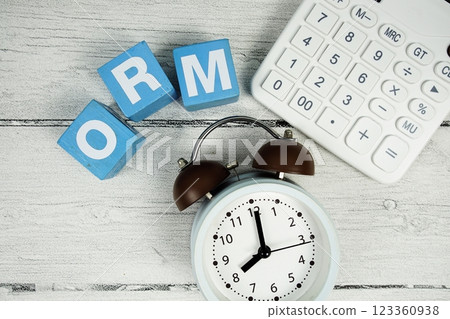 ORM (Online Reputation Management) text with alarm clock and calculator on wooden background 123360938