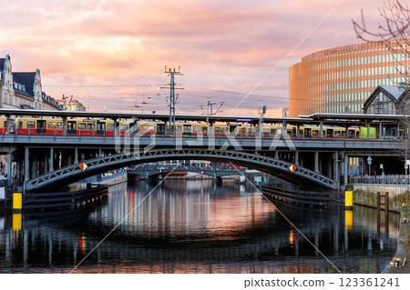 Scenic view Berlin Station Friedrichstrasse train crossing metal bridge against dramatic warm sunset sky. Evening Berlin Mitte river Spree scene urban cityscape architecture landmark Scenic view Berlin Station Friedrichstrasse train crossing metal bridge against dramatic warm sunset sky. Evening Berlin Mitte river Spree scene urban cityscape architecture landmark 123361241