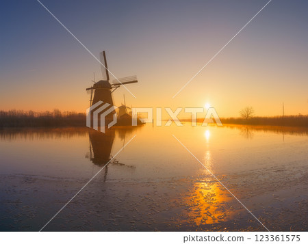 Windmills in the Netherlands during sunrise. Foggy morning and sunshine. Dutch canals. Windmills in the Netherlands during sunrise. Foggy morning and sunshine. Dutch canals. 123361575