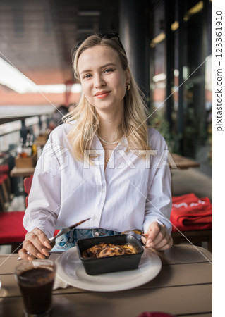 Blonde gen z woman eating lasagna in the cafe on break. Gen z girl spend time in restaurant Blonde gen z woman eating lasagna in the cafe on break. Gen z girl spend time in restaurant 123361910