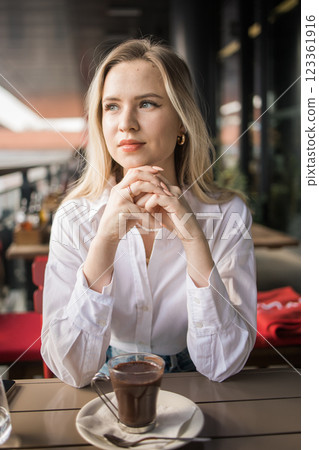 Gen z blonde woman drinks hot chocolate in summer cafe. Tasty beverage and break concept. Generation z people Gen z blonde woman drinks hot chocolate in summer cafe. Tasty beverage and break concept. Generation z people 123361916