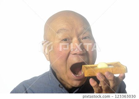 An elderly man eating toasted bread with a smile 123363030