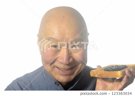 一位老人微笑著吃著烤麵包 一位老人微笑著吃著烤麵包 123363034
