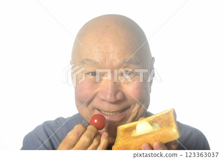 An elderly man eating toasted bread with a smile 123363037