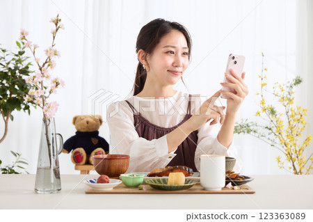 A woman looking at her smartphone at breakfast A woman looking at her smartphone at breakfast 123363089
