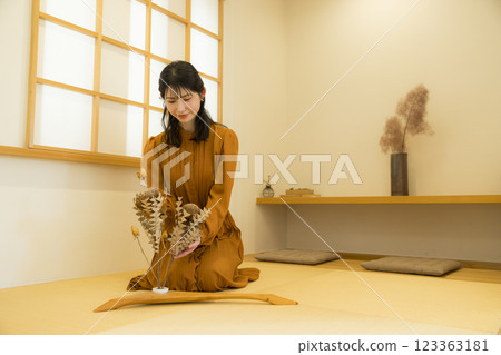 A woman sitting upright in a Japanese-style room 123363181