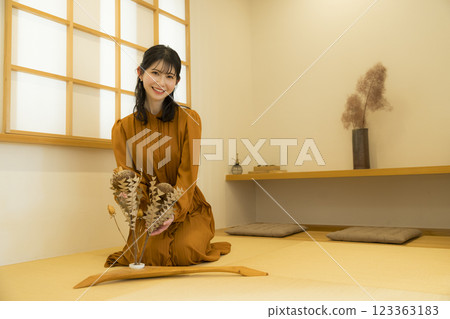 A woman sitting upright in a Japanese-style room 123363183