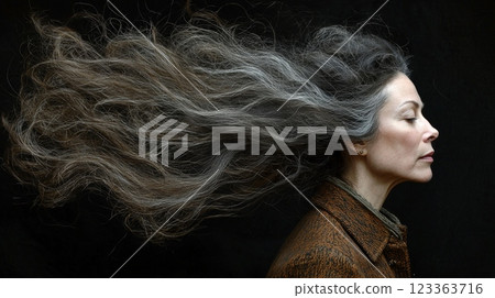 stylist works on client's hair using high speed hairdryer creating dynamic look. dramatic dark background enhances beauty of hair in motion and captures stylish atmosphere. 123363716