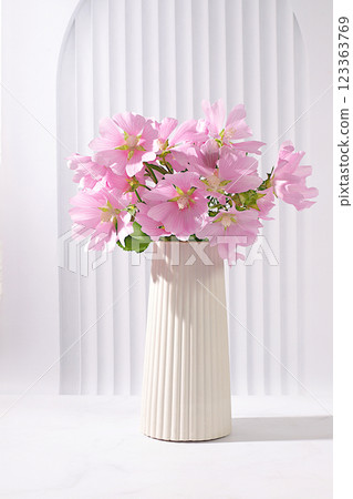 Beautiful mallow flowers in a vase on an elegant modern background, summer banner for product advertising, abstract floral arrangement, holiday card, selective focus. Beautiful mallow flowers in a vase on an elegant modern background, summer banner for product advertising, abstract floral arrangement, holiday card, selective focus. 123363769