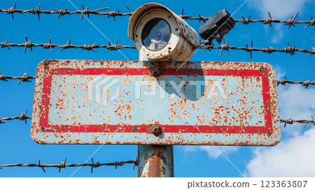 heavy steel gate displays bold red and white no trespassing sign slightly scratched. Barbed wire and security cameras above emphasize strict access restrictions. heavy steel gate displays bold red and white no trespassing sign slightly scratched. Barbed wire and security cameras above emphasize strict access restrictions. 123363807