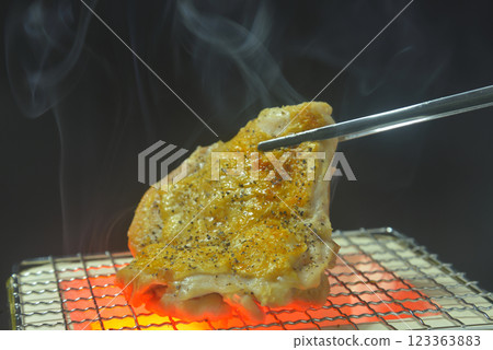 Grilling chicken thighs on a smoky charcoal grill 123363883