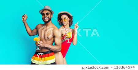 Black man and woman, dressed in swimwear, are smiling and holding cocktails. They are enjoying a summer vacation and having a good time. They are both wearing sunglasses and hats Black man and woman, dressed in swimwear, are smiling and holding cocktails. They are enjoying a summer vacation and having a good time. They are both wearing sunglasses and hats 123364574