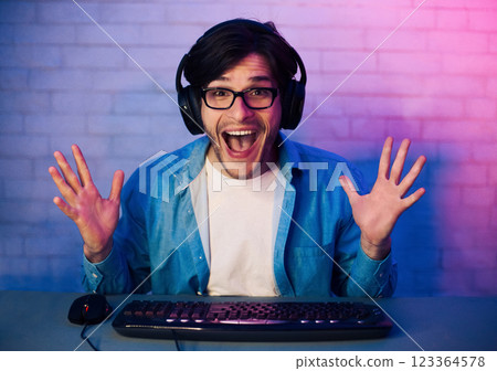 Happy Delighted Young Man Wearing Eyeglasses Gamer Winning Online Computer Game, Looking At Camera Happy Delighted Young Man Wearing Eyeglasses Gamer Winning Online Computer Game, Looking At Camera 123364578