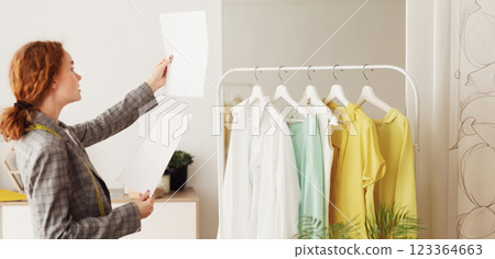 Young Designer Checking And Comparing Sketches On Papers, Working In Tailor Studio Young Designer Checking And Comparing Sketches On Papers, Working In Tailor Studio 123364663