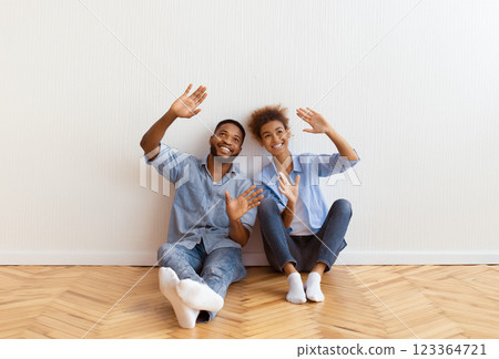Renovation In New Home. Smiling Afro Couple Planning Interior Design Sitting On Floor After Moving Into Own House 123364721