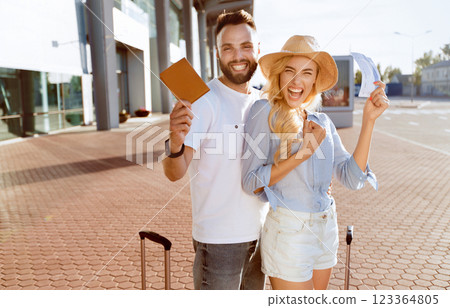 Ready For Vacation. Excited spouses with suitcases showing boarding passes and passports, standing near airport Ready For Vacation. Excited spouses with suitcases showing boarding passes and passports, standing near airport 123364805