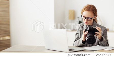 Reporter off loading files from camera to laptop, working in office, copy space Reporter off loading files from camera to laptop, working in office, copy space 123364877