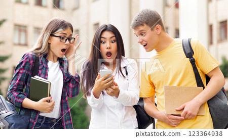 Shocked students checking exams results online on smartphone, resting in campus Shocked students checking exams results online on smartphone, resting in campus 123364938