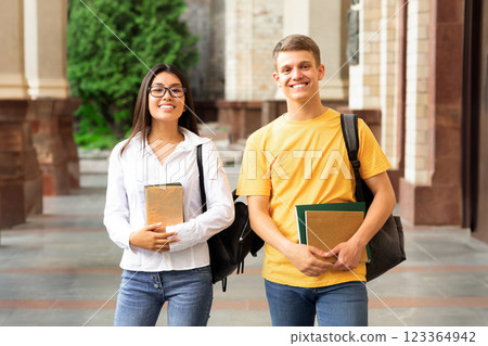 Happy college classmates having break in university campus, smiling to camera outdoors Happy college classmates having break in university campus, smiling to camera outdoors 123364942