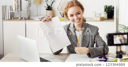 Fashion designer recording video for her blog, showing sketches to subscribers 123364989