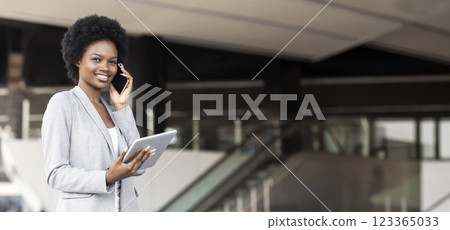Pensive young woman talking on cell phone, using digital tablet near modern office building 123365033