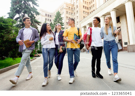Free time of students. Friends walking after classes against university building 123365041