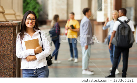 University life. Happy asian girl holding books and smiling, resting between classes University life. Happy asian girl holding books and smiling, resting between classes 123365181