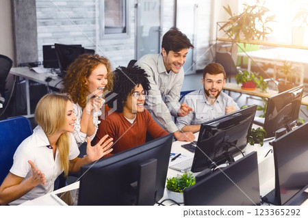 Win grant. Excited students reading good news together on computer screen in modern coworking office, enjoying their friend's success, free space 123365292