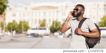 Young african american tourist with backpack calling his frients to meet with them outdoor, panorama, copy space Young african american tourist with backpack calling his frients to meet with them outdoor, panorama, copy space 123365576
