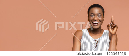African American young woman with a big, genuine smile. The woman has a thoughtful expression on her face and is pointing her index finger up. African American young woman with a big, genuine smile. The woman has a thoughtful expression on her face and is pointing her index finger up. 123365618