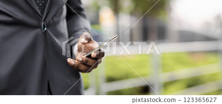 Busy businessman using smartphone browsing internet and drinking take-out coffee outdoors, closeup Busy businessman using smartphone browsing internet and drinking take-out coffee outdoors, closeup 123365627