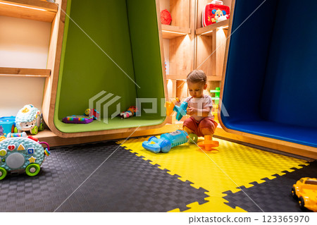 Toddler playing with toys in a colorful and modern playroom designed for learning and creativity Toddler playing with toys in a colorful and modern playroom designed for learning and creativity 123365970
