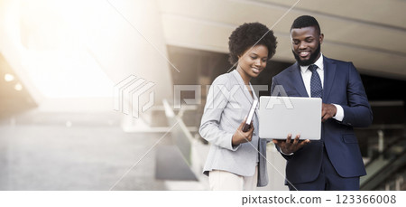 Business man and woman using laptop outdoors in modern urban setting, free space Business man and woman using laptop outdoors in modern urban setting, free space 123366008