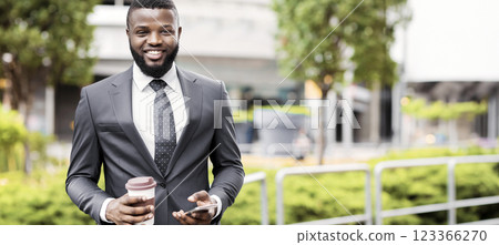 Portrait of cheerful african employee having coffee break and using smartphone outdoors, empty space 123366270