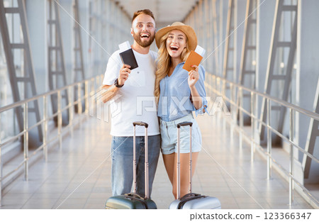 Ready For Vacation. Excited spouses with suitcases holding boarding passes and smiling, standing in airport Ready For Vacation. Excited spouses with suitcases holding boarding passes and smiling, standing in airport 123366347