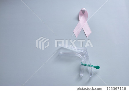 Gynecological mirror and pink ribbon are a sign of support for oncology in breast cancer 123367116