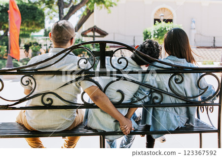 Unfaithful couple holding hands on a park bench, Cheating girlfriend with her boyfriend holding another man's hand in a park. love triangle concept 123367592