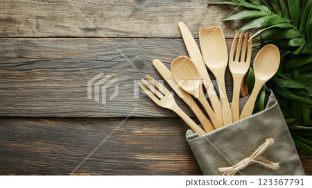 Bamboo Cutlery Set in Fabric Case on Wooden Table Surrounded by Greenery 123367791